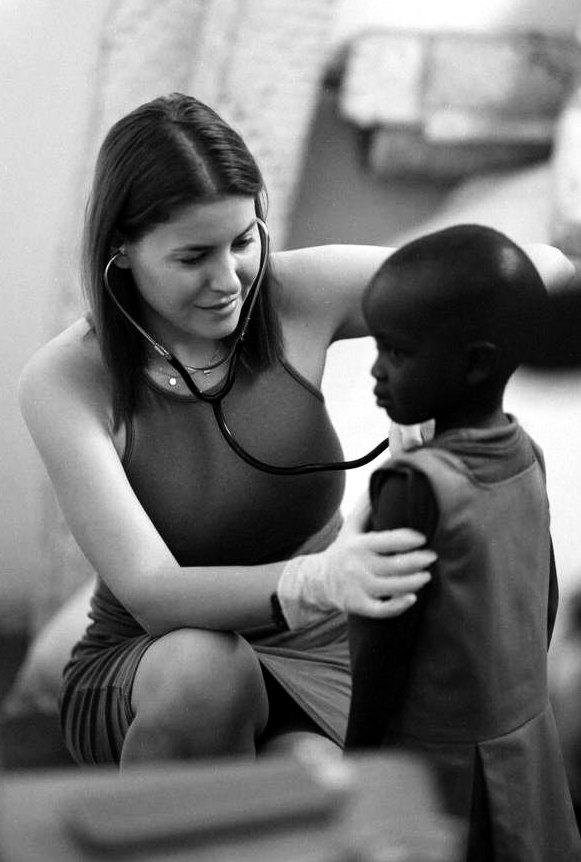 Yulia Agranovych listening to a child’s chest with a stethoscope during the medical mission in Kenya, black-and-white photograph