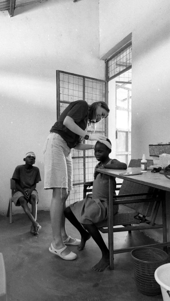 Yulia Agranovych checking a dressing on a girl’s head during the medical mission in Kenya, black-and-white photograph