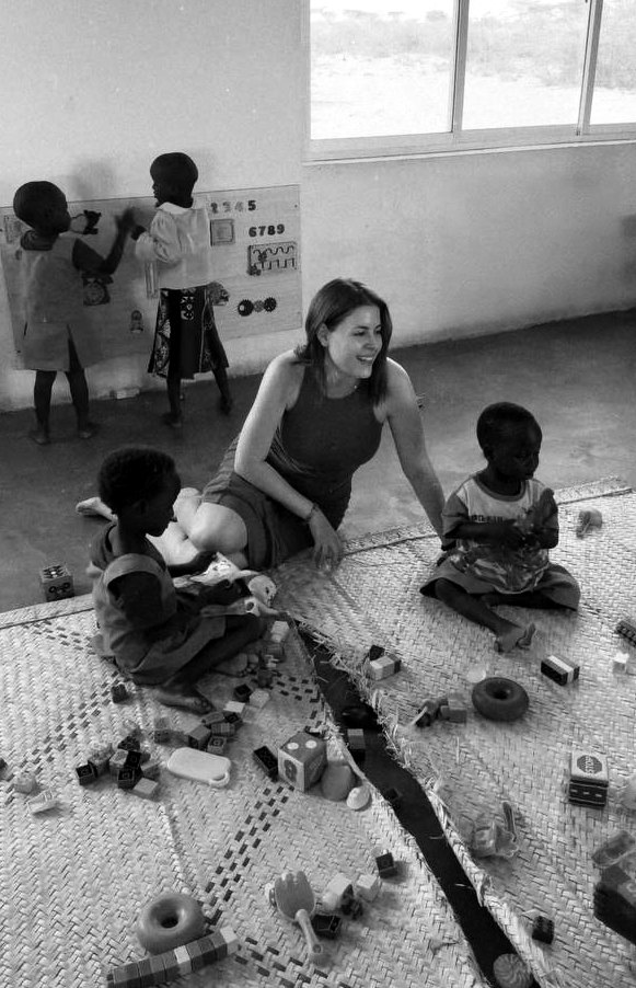 Yulia Agranovych playing with children on a mat with toys during the medical mission in Kenya, black-and-white photograph