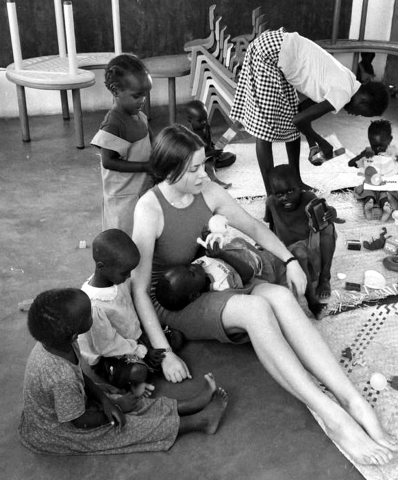 Yulia Agranovych sitting on the floor surrounded by children during the medical mission in Kenya, black-and-white photograph