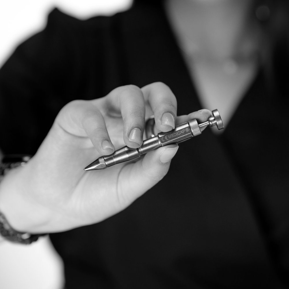 Close-up of a doctor’s hand holding a hair transplant instrument, black-and-white photograph